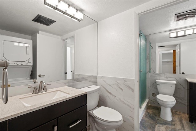 bathroom featuring visible vents, stacked washer / dryer, a textured ceiling, and toilet