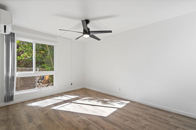 spare room featuring a ceiling fan, baseboards, wood finished floors, and a wall mounted air conditioner