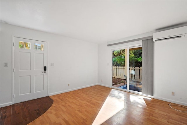 entrance foyer featuring an AC wall unit, light wood finished floors, and baseboards