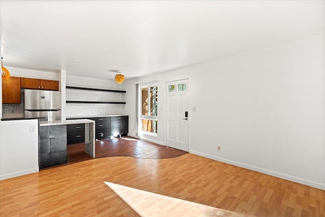 unfurnished living room with light wood finished floors and baseboards