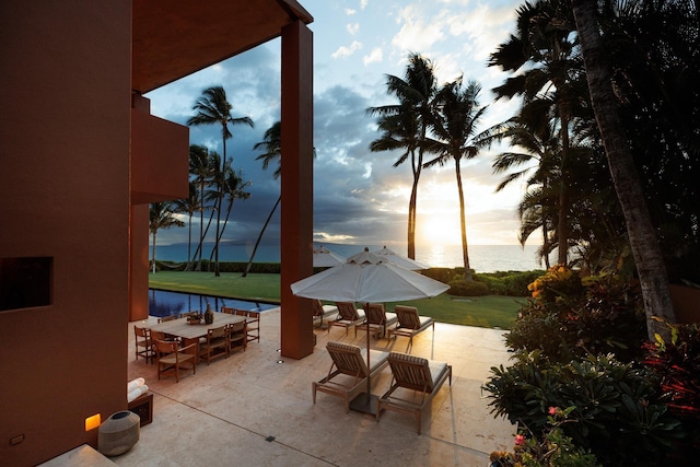 patio terrace at dusk featuring outdoor dining space and a water view