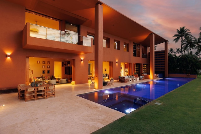 pool at dusk with an outdoor pool, an in ground hot tub, stairs, a patio area, and an outdoor living space