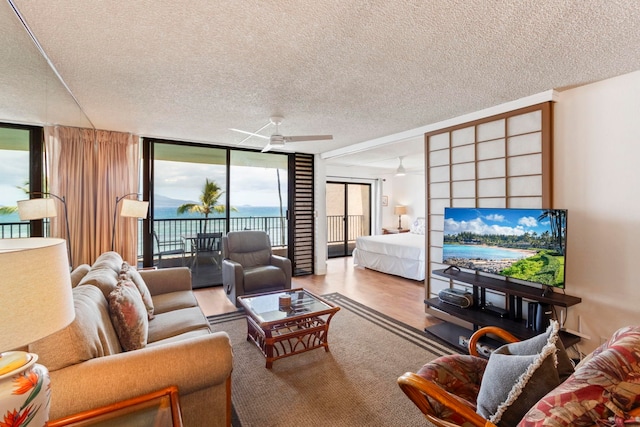 100 Hauoli St Unit 303, Wailuku, HI 96793 - living room featuring a wall of windows, a textured ceiling, ceiling fan, wood finished floors, and plenty of natural light