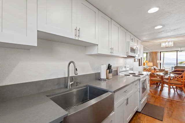 100 Hauoli St Unit 303, Wailuku, HI 96793 - kitchen featuring white appliances, white cabinets, wood finished floors, recessed lighting, and a chandelier