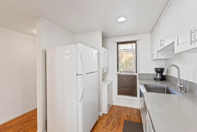 100 Hauoli St Unit 303, Wailuku, HI 96793 - kitchen with freestanding refrigerator, stacked washing machine and dryer, white cabinetry, light wood-style flooring, and light countertops