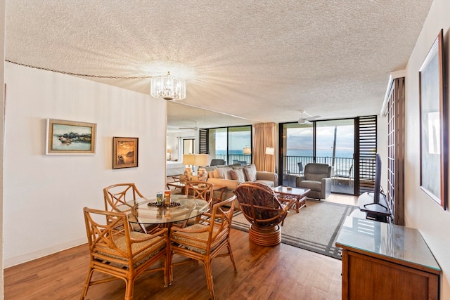 100 Hauoli St Unit 303, Wailuku, HI 96793 - dining space featuring wood finished floors, a textured ceiling, a chandelier, a water view, and expansive windows