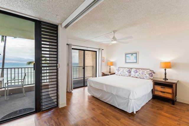 100 Hauoli St Unit 303, Wailuku, HI 96793 - bedroom with access to outside, a textured ceiling, wood finished floors, a water view, and a wall of windows