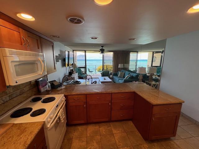 4471 Lower Honoapiilani Rd Unit 202, Lahaina, HI 96761 - kitchen with white appliances, a peninsula, open floor plan, brown cabinetry, and recessed lighting