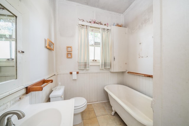 full bathroom featuring a sink, a wainscoted wall, tile patterned floors, toilet, and a soaking tub
