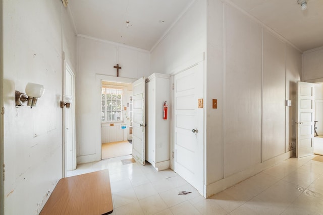 hall with light floors and ornamental molding