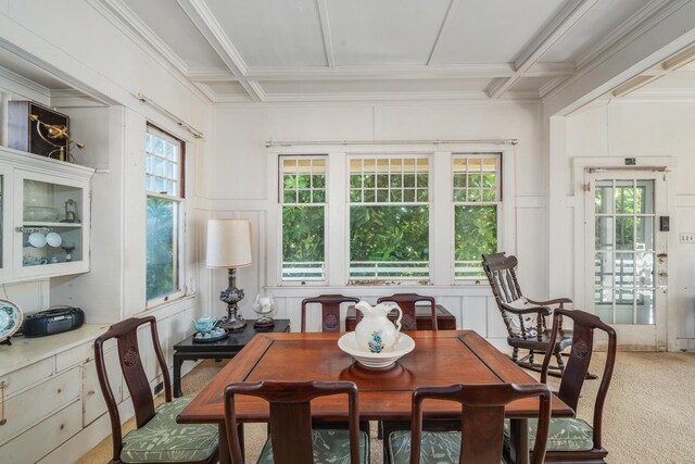 dining room with coffered ceiling, light colored carpet, a healthy amount of sunlight, and a decorative wall