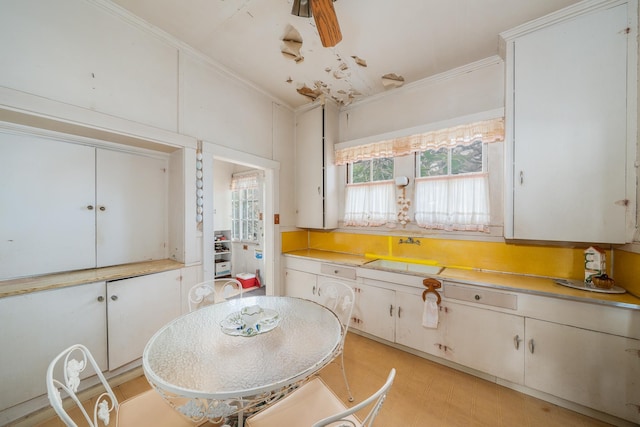 kitchen featuring crown molding, light countertops, a sink, and light floors