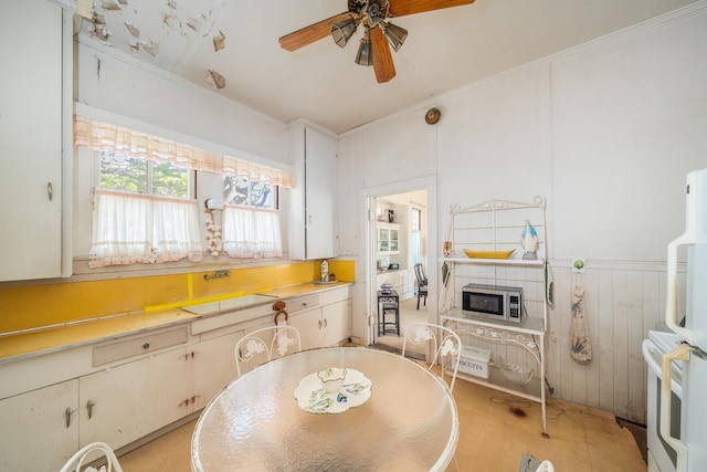 kitchen featuring a ceiling fan, crown molding, stove, light countertops, and stainless steel microwave