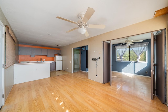 unfurnished living room with light wood-type flooring, a sink, and ceiling fan