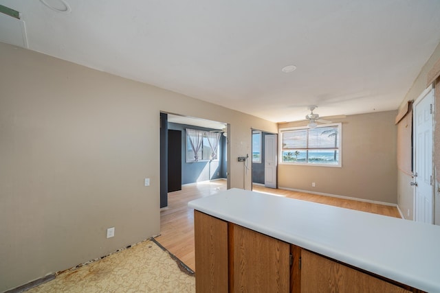 kitchen with baseboards, ceiling fan, light countertops, brown cabinets, and light wood-style flooring