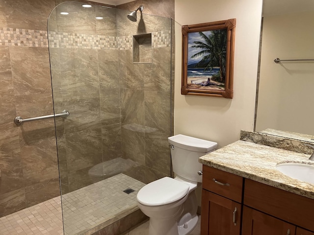 bathroom featuring vanity, toilet, and a tile shower