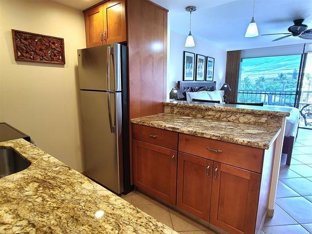 kitchen featuring light tile patterned floors, light stone countertops, and stainless steel refrigerator