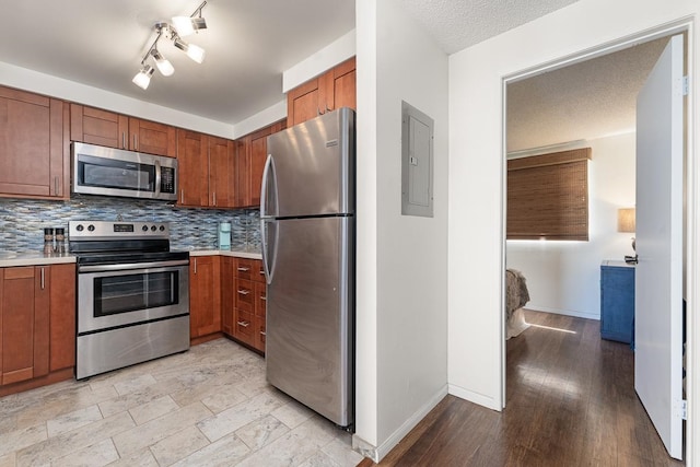 kitchen with a textured ceiling, light wood-type flooring, appliances with stainless steel finishes, tasteful backsplash, and track lighting