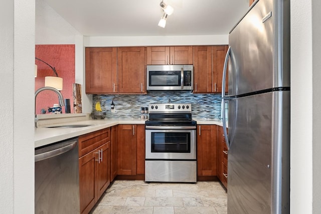 kitchen featuring stainless steel appliances, light tile flooring, backsplash, rail lighting, and sink