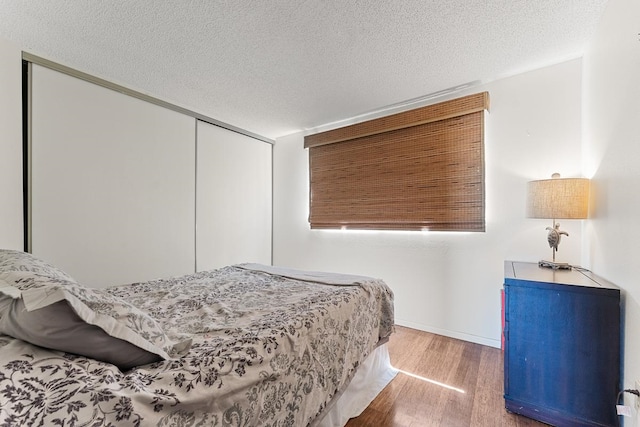 bedroom with wood-type flooring, a closet, and a textured ceiling