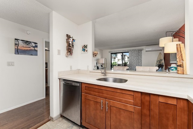 kitchen with light hardwood / wood-style floors, an AC wall unit, stainless steel dishwasher, sink, and a textured ceiling