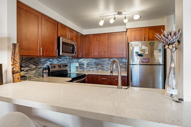 kitchen featuring appliances with stainless steel finishes, backsplash, kitchen peninsula, and rail lighting