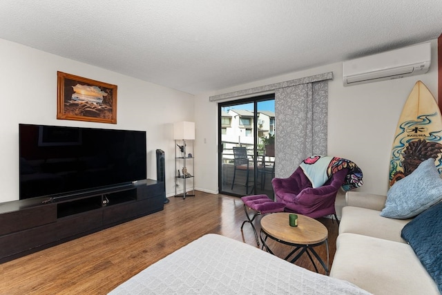 living room featuring hardwood / wood-style flooring, a wall unit AC, and a textured ceiling