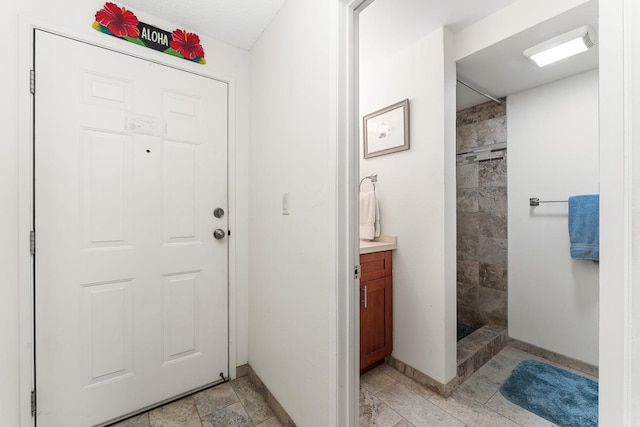 bathroom with tile floors, a tile shower, and vanity