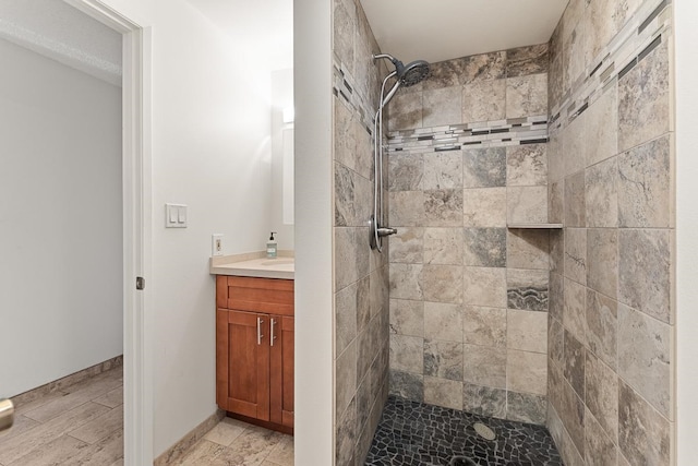 bathroom featuring a tile shower, tile flooring, and vanity