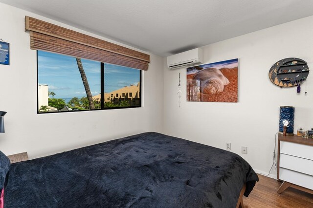 bedroom with hardwood / wood-style flooring and an AC wall unit