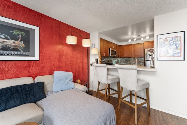 bedroom with stainless steel refrigerator, dark hardwood / wood-style floors, track lighting, sink, and a textured ceiling