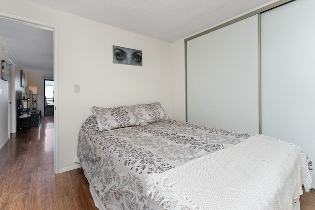 bedroom featuring a closet, a textured ceiling, and dark wood-type flooring