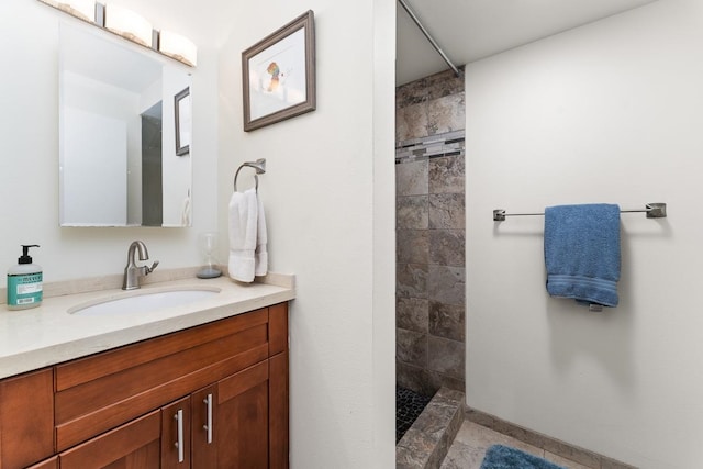 bathroom with tiled shower, tile flooring, and vanity