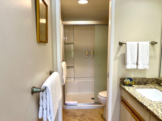 bathroom featuring tile patterned floors, vanity, toilet, and a shower with shower door