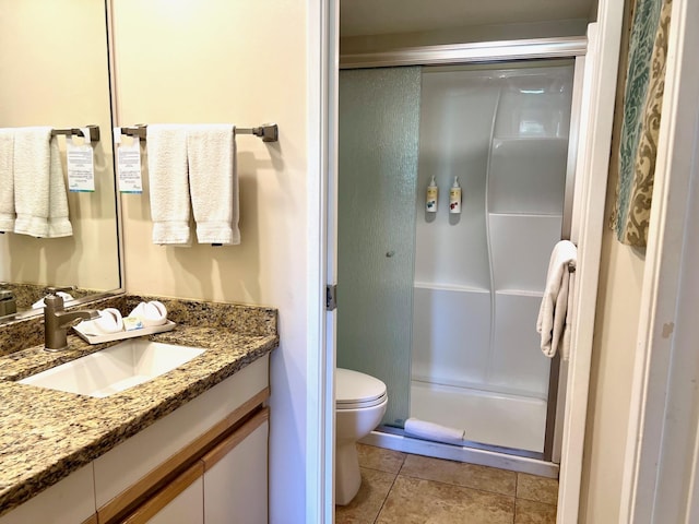 bathroom featuring tile patterned flooring, vanity, toilet, and walk in shower