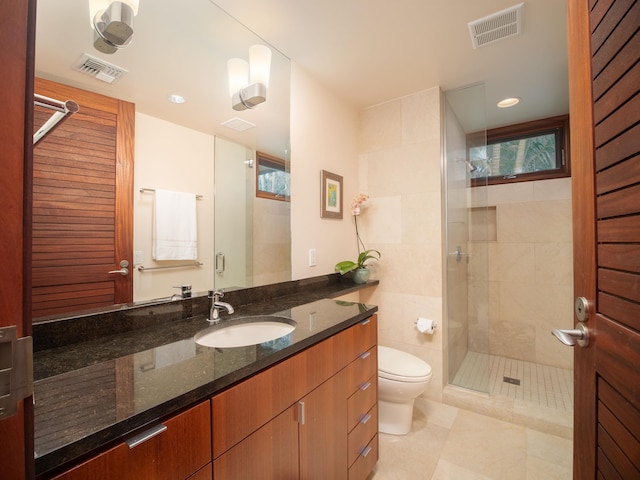 bathroom with toilet, vanity, tile patterned floors, and a shower with door