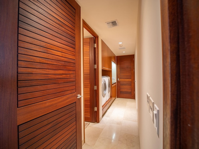 corridor featuring separate washer and dryer and wooden walls