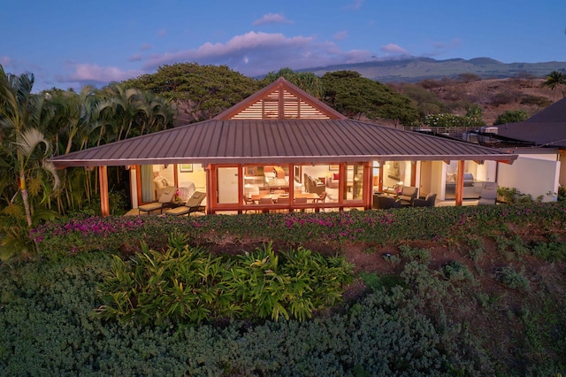 back house at dusk featuring a mountain view and an outdoor hangout area