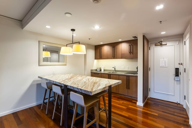 kitchen featuring a kitchen breakfast bar, dark hardwood / wood-style flooring, kitchen peninsula, and sink