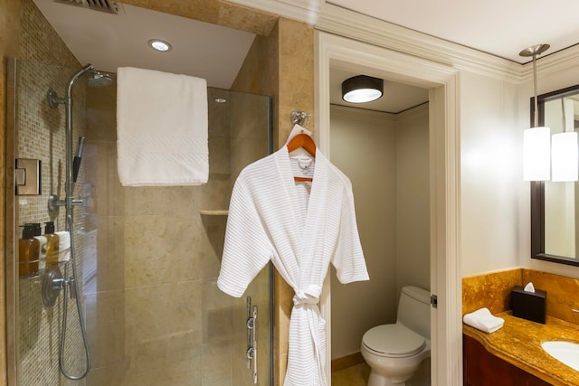 bathroom featuring tiled shower, crown molding, vanity, and toilet