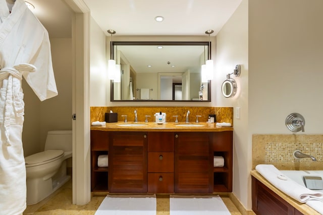 bathroom featuring decorative backsplash, a washtub, vanity, and toilet