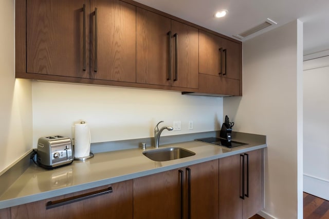 kitchen with black electric stovetop, sink, and dark wood-type flooring