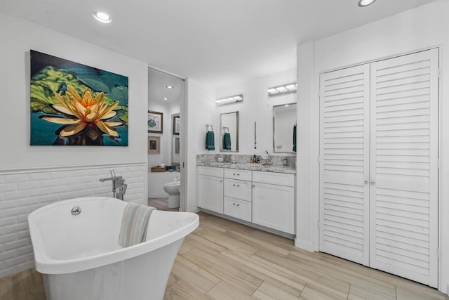 bathroom featuring vanity, a bathtub, toilet, and tile walls