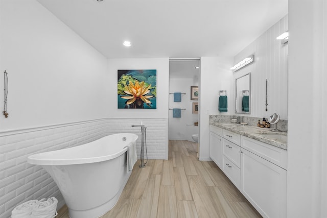 bathroom featuring a tub, hardwood / wood-style floors, vanity, tile walls, and toilet