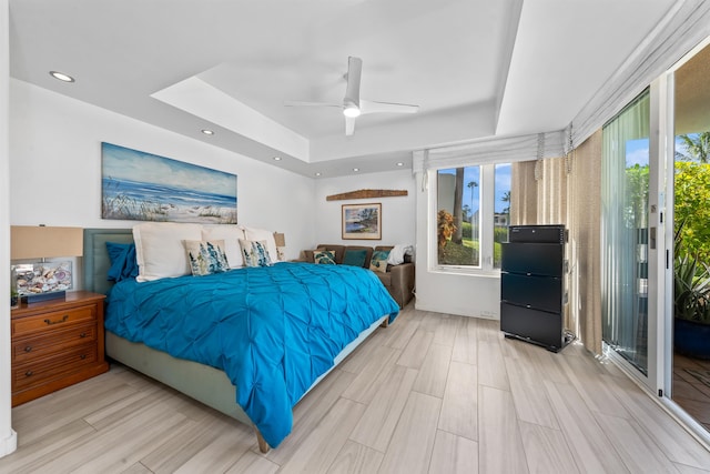 bedroom featuring ceiling fan, a raised ceiling, access to exterior, and light hardwood / wood-style flooring