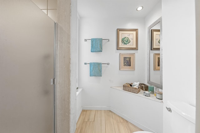 bathroom with a shower with door and toilet