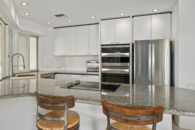 kitchen featuring kitchen peninsula, appliances with stainless steel finishes, and a kitchen breakfast bar