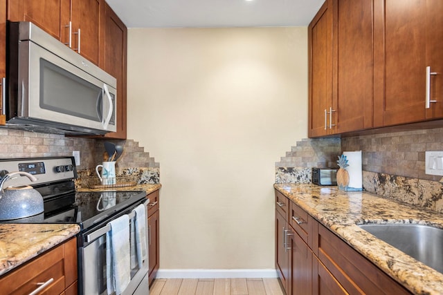 140 Uwapo Rd Unit 9-103, Kihei, HI 96753 - kitchen featuring appliances with stainless steel finishes, backsplash, light stone countertops, and brown cabinets