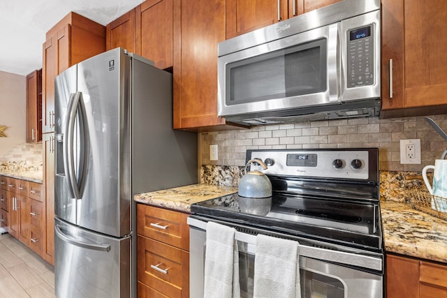 140 Uwapo Rd Unit 9-103, Kihei, HI 96753 - kitchen featuring appliances with stainless steel finishes, brown cabinetry, backsplash, and light stone counters