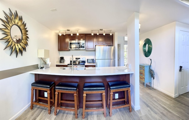 kitchen with dark hardwood / wood-style flooring, a breakfast bar area, kitchen peninsula, and appliances with stainless steel finishes